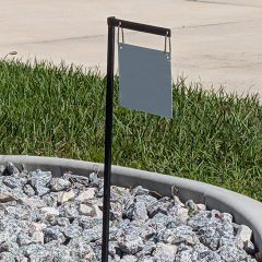 Low-profile black metal real estate yard arm sign frame installed on a grassy lawn.
